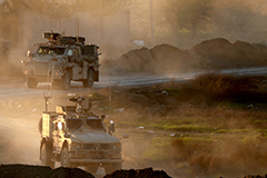 Military trucks on dusty road in the Middle East