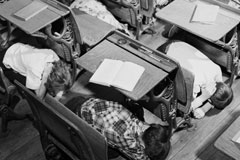 School children learned to protect themselves in case of nuclear attack by practicing a duck and cover drill in the classroom of their school.