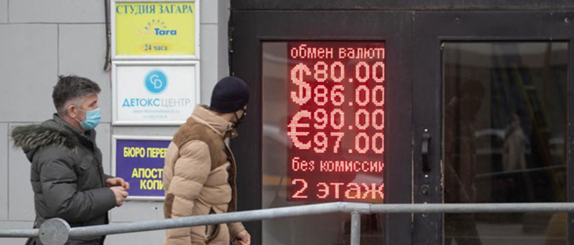 Two men on the street outside a building with the exchange rate in neon signs