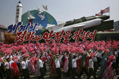 North Koreans parade in Pyongyang in 2017 alongside a float with model missiles and rockets and the message, "For Peace and Stability in the World." (Wong Maye-E / Associated Press)