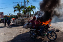 Men on a motocycle in front of burning tires