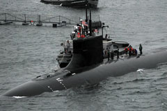 US Navy Submarine partially submerged under water, people walking on top of it